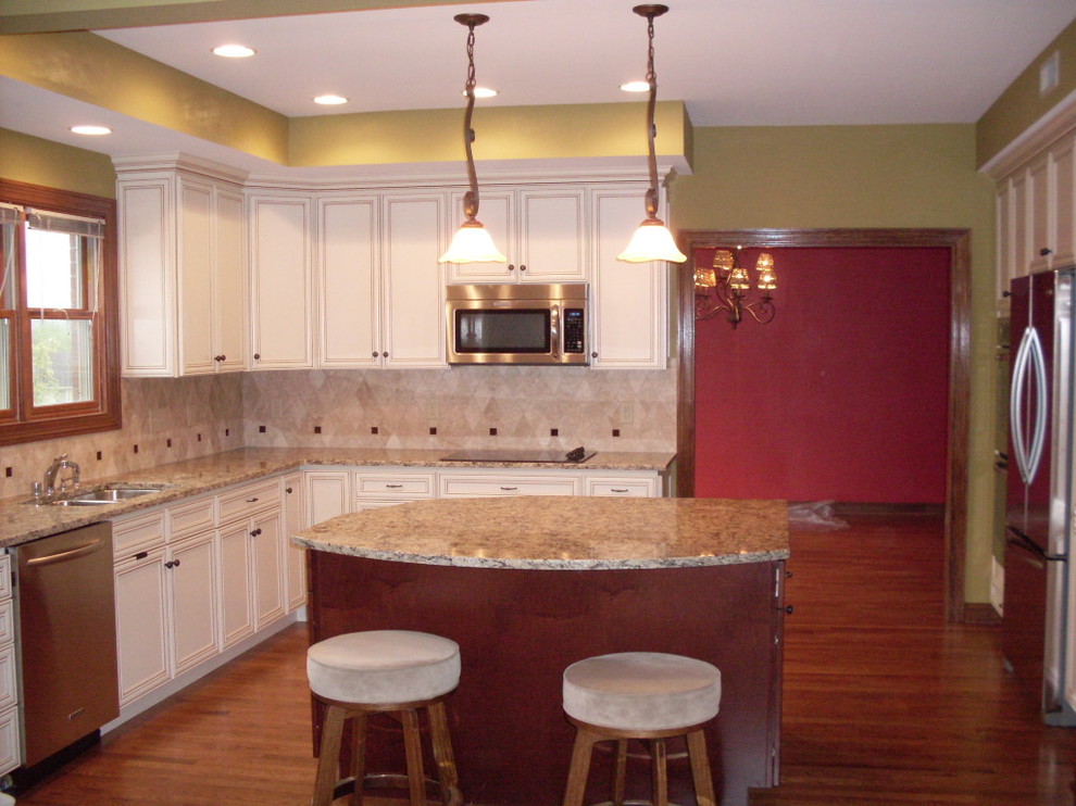 Inspiration for a mid-sized transitional u-shaped dark wood floor open concept kitchen remodel in Cincinnati with an undermount sink, recessed-panel cabinets, white cabinets, granite countertops, beige backsplash, ceramic backsplash, stainless steel appliances and an island