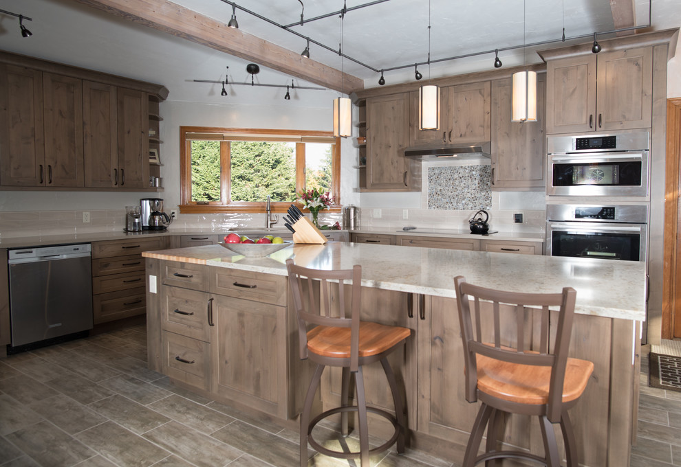 Example of a mid-sized mountain style l-shaped porcelain tile, brown floor and exposed beam open concept kitchen design in Seattle with an undermount sink, recessed-panel cabinets, gray cabinets, quartz countertops, beige backsplash, ceramic backsplash, stainless steel appliances, an island and beige countertops