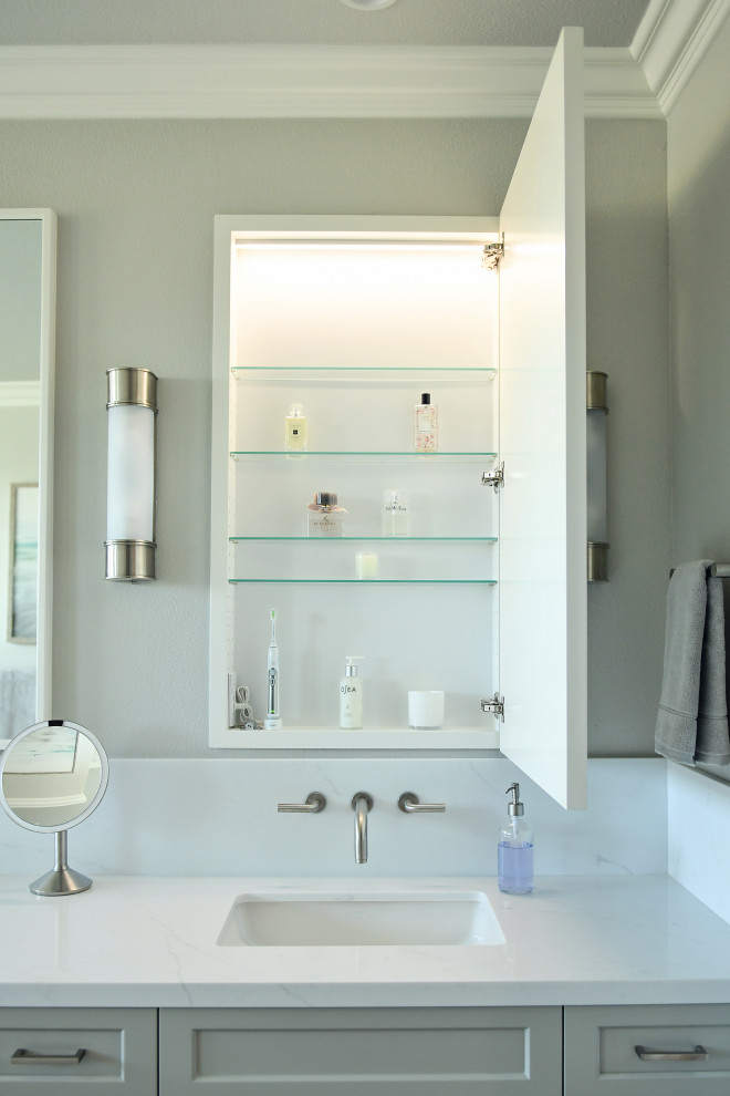 This is an example of a large transitional master bathroom in San Diego with shaker cabinets, grey cabinets, a freestanding tub, white tile, marble, grey walls, an undermount sink, engineered quartz benchtops, grey floor, a hinged shower door, white benchtops, a double vanity, a built-in vanity, a corner shower, a bidet, ceramic floors and a niche.