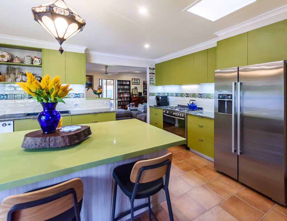 Photo of a mid-sized eclectic kitchen in Melbourne with a drop-in sink, flat-panel cabinets, green cabinets, laminate benchtops, multi-coloured splashback, ceramic splashback, stainless steel appliances, ceramic floors and with island.