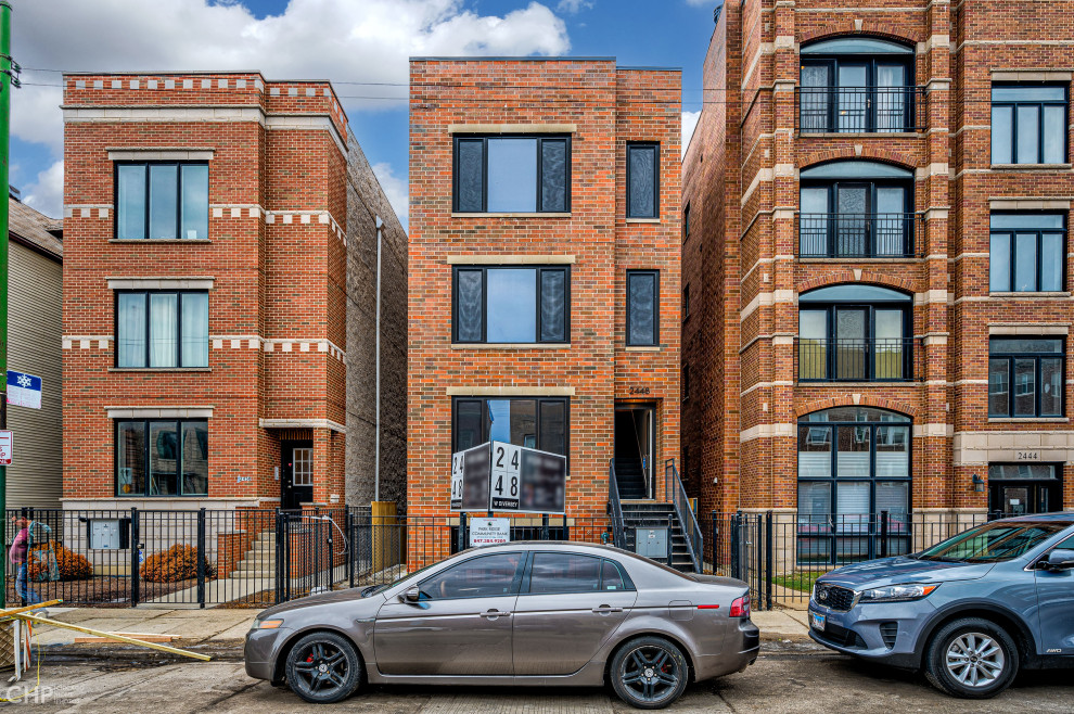 This is an example of an expansive contemporary brick red apartment exterior in Chicago with four or more storeys.