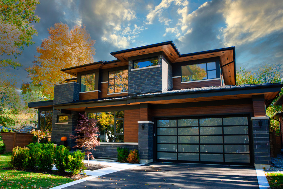 This is an example of a mid-sized contemporary two-storey black house exterior in Toronto with mixed siding, a metal roof, a black roof and clapboard siding.