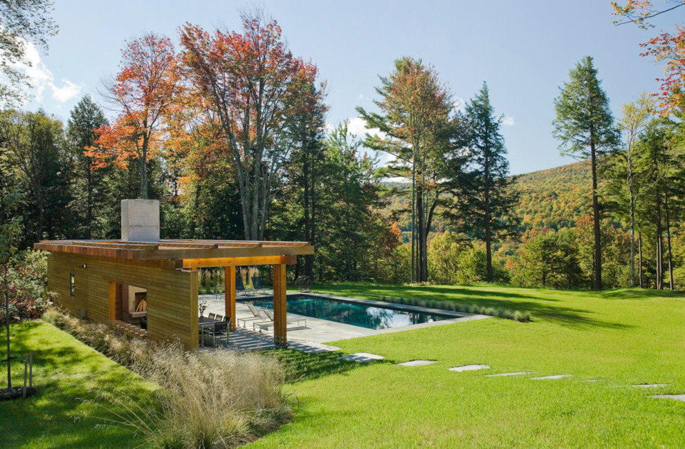 This is an example of a large modern backyard rectangular lap pool in Burlington with natural stone pavers and a pool house.