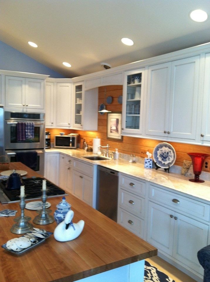 Example of a transitional l-shaped light wood floor eat-in kitchen design in Boston with an undermount sink, shaker cabinets, white cabinets, granite countertops, stainless steel appliances, an island, brown backsplash and wood backsplash