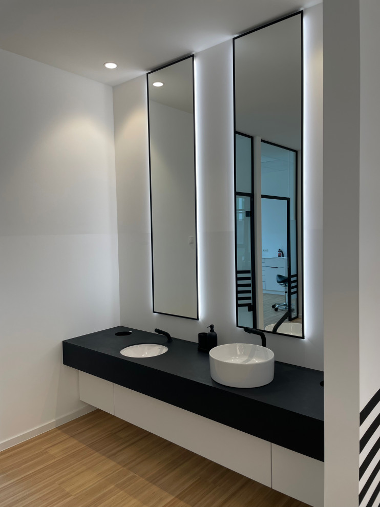 Foto de cuarto de baño doble y a medida minimalista pequeño con armarios con paneles lisos, puertas de armario blancas, paredes blancas, suelo de bambú, encimera de cemento, suelo marrón y encimeras negras