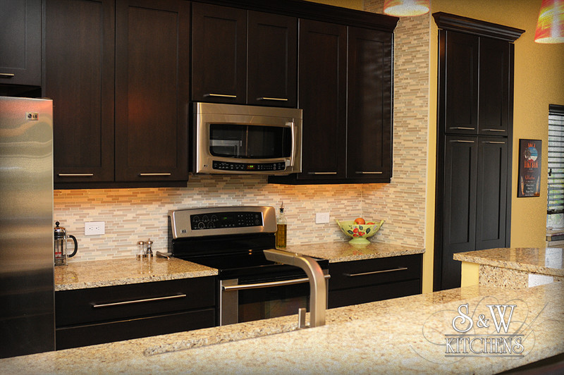 Transitional galley kitchen photo in Orlando with a single-bowl sink, shaker cabinets, dark wood cabinets, granite countertops, beige backsplash, mosaic tile backsplash and stainless steel appliances