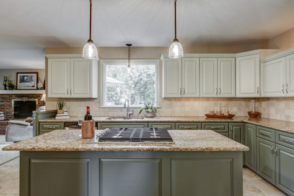 Example of a mid-sized transitional l-shaped ceramic tile and beige floor eat-in kitchen design with a double-bowl sink, raised-panel cabinets, green cabinets, granite countertops, beige backsplash, ceramic backsplash, stainless steel appliances, an island and beige countertops