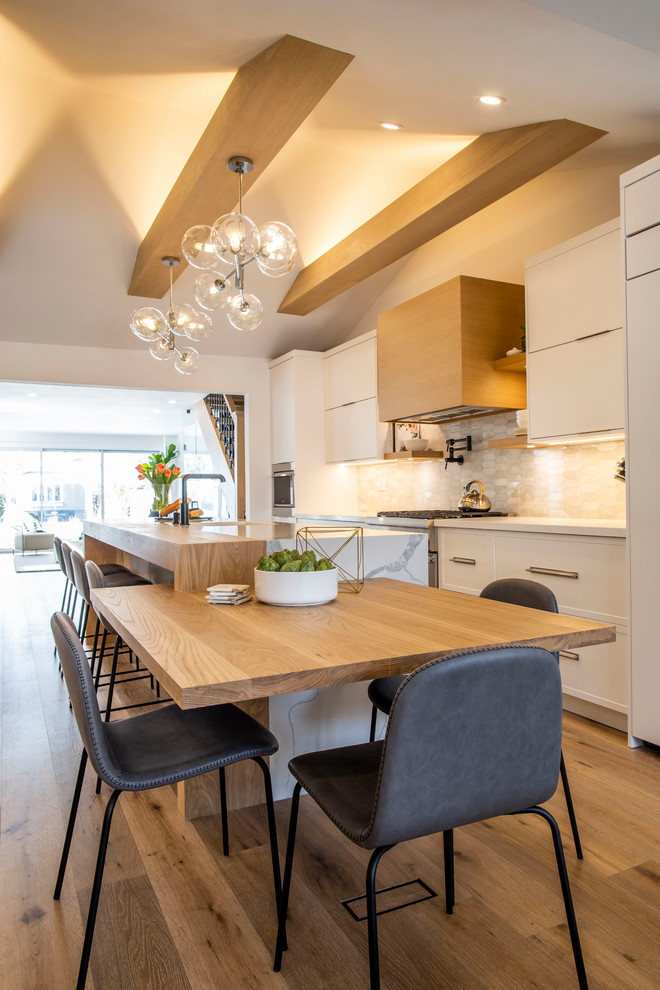 Photo of a mid-sized contemporary single-wall open plan kitchen in Toronto with flat-panel cabinets, white cabinets, with island, an undermount sink, quartz benchtops, panelled appliances, light hardwood floors, brown floor and white benchtop.