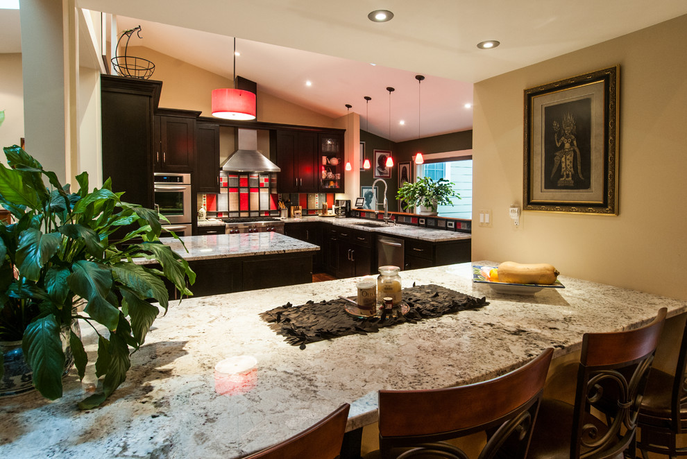Example of a transitional u-shaped open concept kitchen design in DC Metro with an undermount sink, shaker cabinets, dark wood cabinets, granite countertops, red backsplash, glass tile backsplash and stainless steel appliances