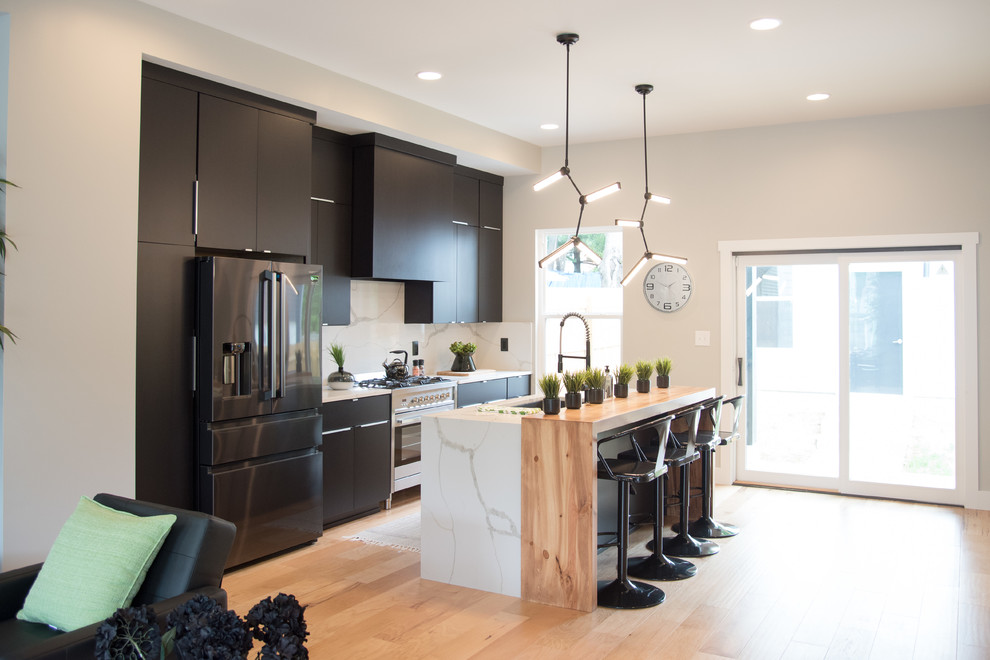 Contemporary galley kitchen in Indianapolis with flat-panel cabinets, brown cabinets, white splashback, stainless steel appliances, light hardwood floors, with island, brown floor, marble benchtops, marble splashback and white benchtop.