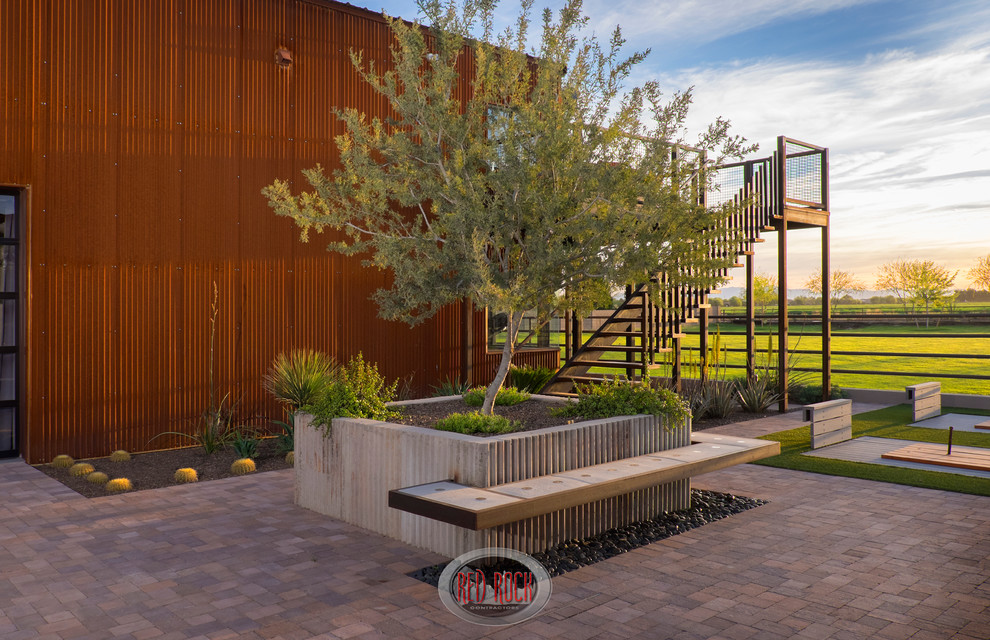 Inspiration for a large industrial backyard partial sun xeriscape in Phoenix with brick pavers.