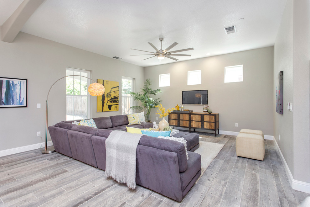 This is an example of a large contemporary open concept living room in Sacramento with grey walls, porcelain floors, no fireplace, a wall-mounted tv and grey floor.
