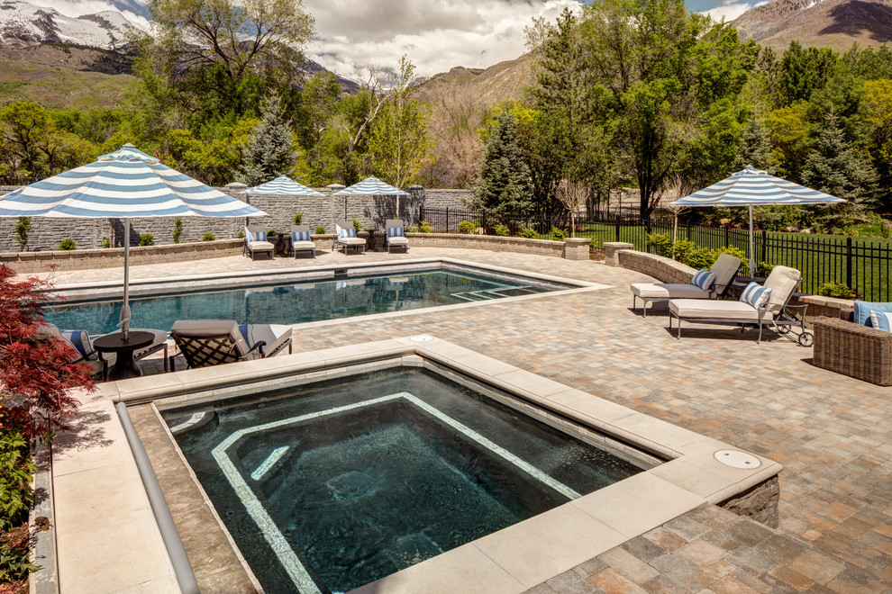 Large traditional backyard rectangular aboveground pool in Salt Lake City with a hot tub and natural stone pavers.