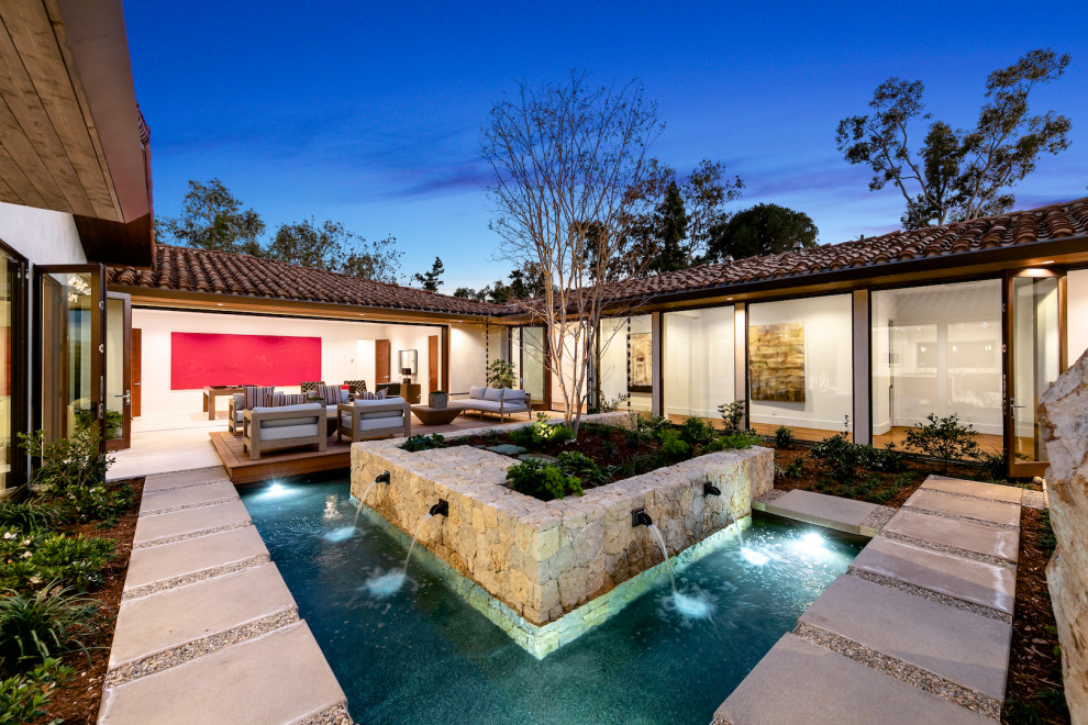 This is an example of a contemporary courtyard full sun garden in San Diego with a water feature.