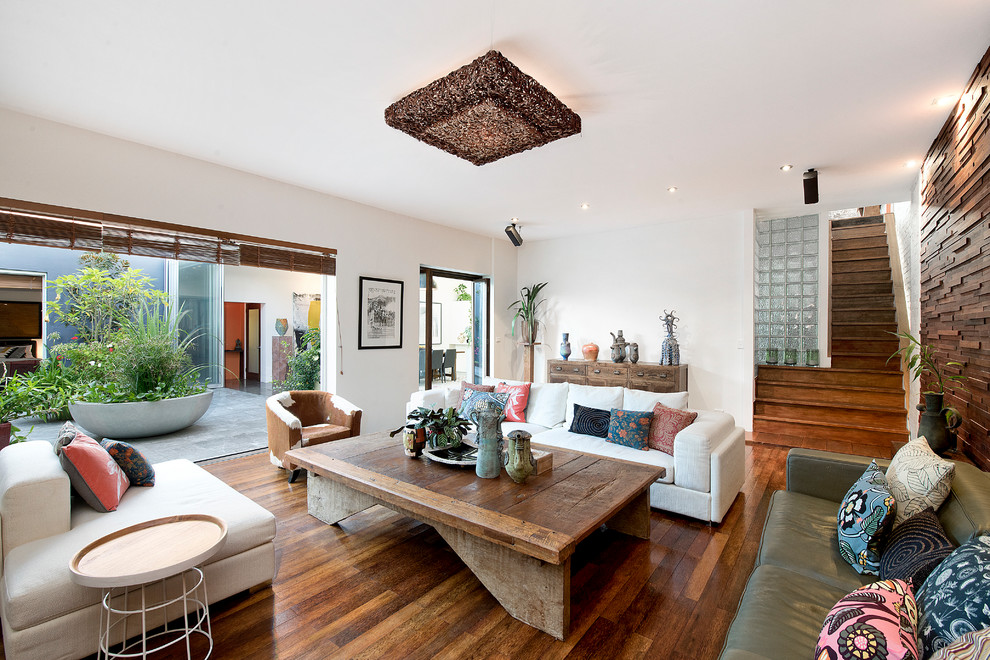 Inspiration for an eclectic family room in Sydney with white walls, medium hardwood floors, brown floor, no fireplace and no tv.