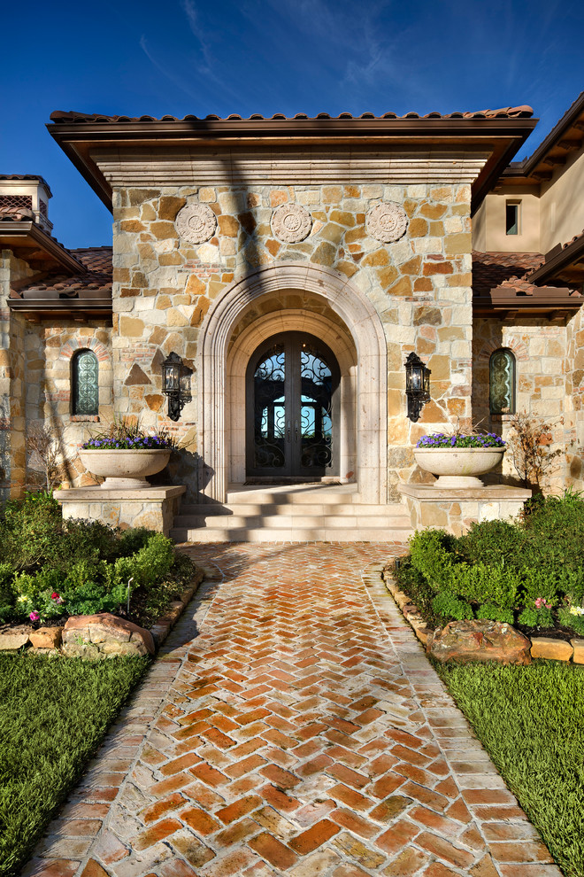 This is an example of a mediterranean front door in Houston with a double front door and a glass front door.