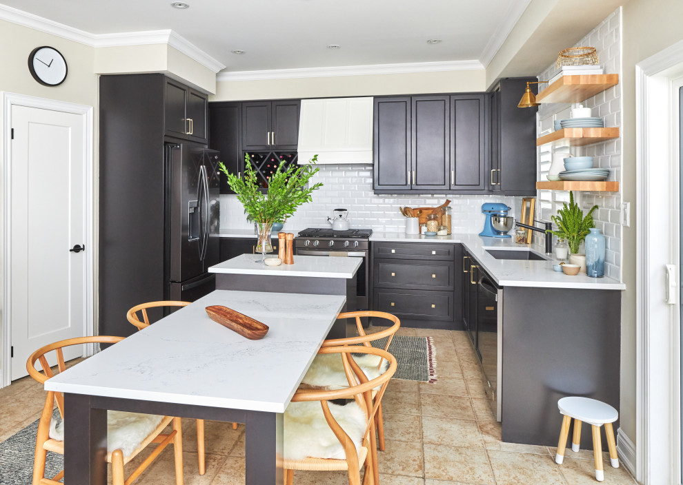 This is an example of a transitional u-shaped kitchen in Toronto with an undermount sink, recessed-panel cabinets, black cabinets, white splashback, subway tile splashback, black appliances, with island, beige floor and white benchtop.