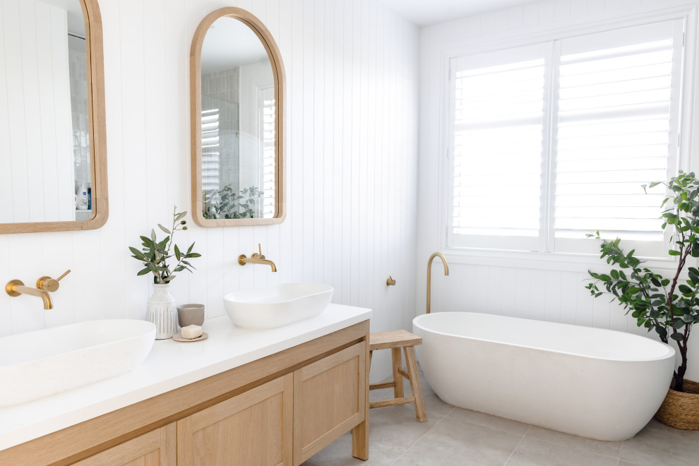 Design ideas for a medium sized beach style family bathroom with shaker cabinets, light wood cabinets, a freestanding bath, a walk-in shower, ceramic flooring, engineered stone worktops, grey floors, an open shower, white worktops, a wall niche, double sinks, a freestanding vanity unit and panelled walls.