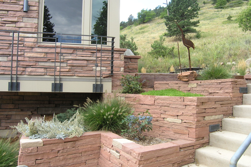 Inspiration for a mid-sized country side yard partial sun garden for summer in Denver with a retaining wall and natural stone pavers.