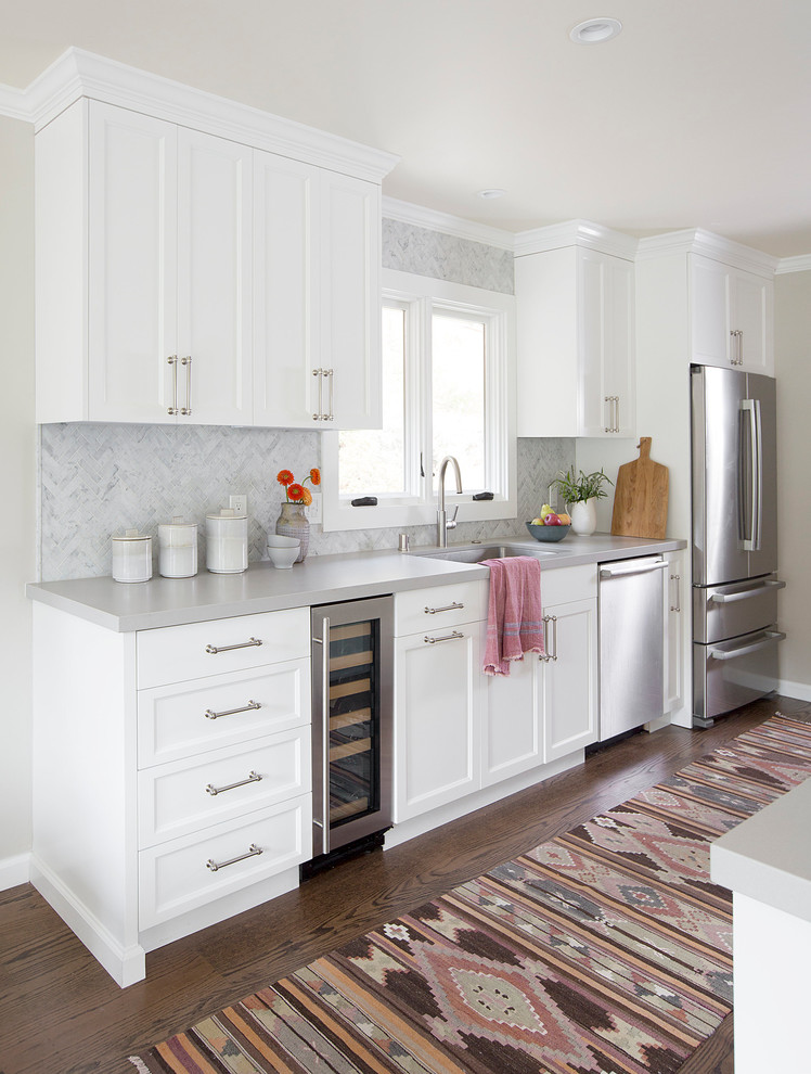 This is an example of a mid-sized transitional galley eat-in kitchen in San Francisco with a single-bowl sink, shaker cabinets, yellow cabinets, quartzite benchtops, white splashback, mosaic tile splashback, stainless steel appliances, medium hardwood floors, with island and brown floor.