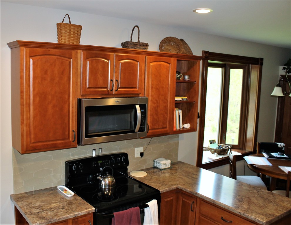 Mid-sized mountain style l-shaped vinyl floor and beige floor eat-in kitchen photo with a farmhouse sink, raised-panel cabinets, medium tone wood cabinets, laminate countertops, beige backsplash, cement tile backsplash, stainless steel appliances, a peninsula and beige countertops