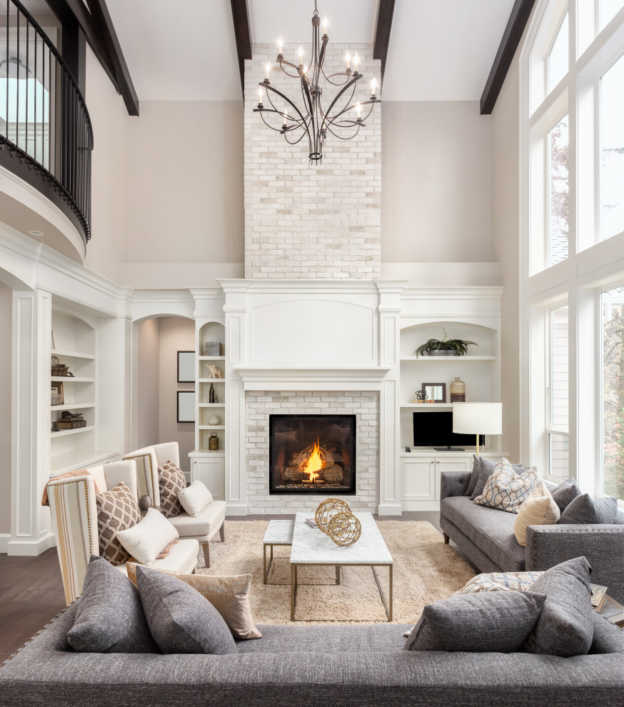 Expansive traditional open plan living room in San Francisco with white walls, medium hardwood flooring, a standard fireplace, a brick fireplace surround, brown floors and exposed beams.