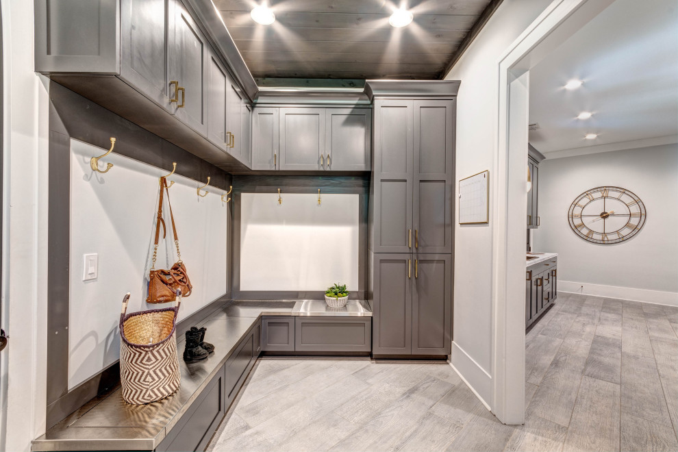 This is an example of an expansive arts and crafts galley utility room in Atlanta with a drop-in sink, shaker cabinets, grey cabinets, laminate benchtops, grey walls, porcelain floors, a side-by-side washer and dryer, grey floor, white benchtop and wood.