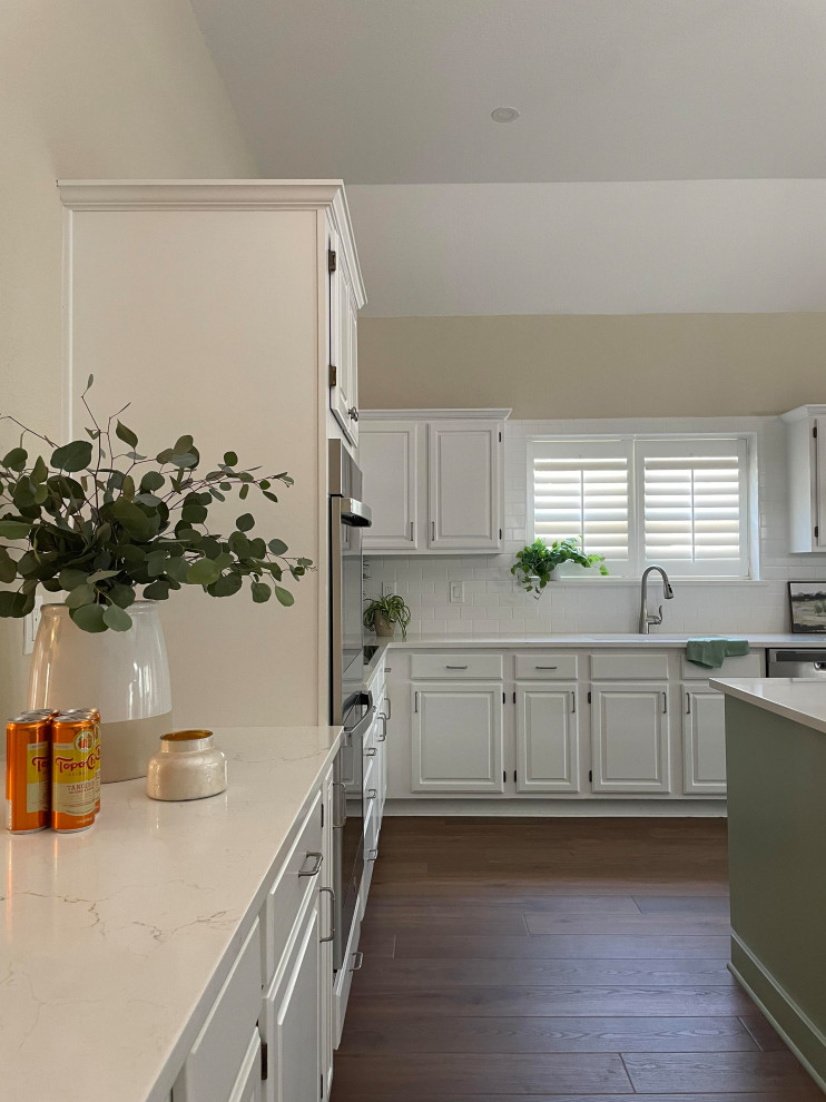 Kitchen - l-shaped vinyl floor and brown floor kitchen idea with a single-bowl sink, white cabinets, white backsplash, subway tile backsplash, stainless steel appliances, an island, white countertops and quartz countertops
