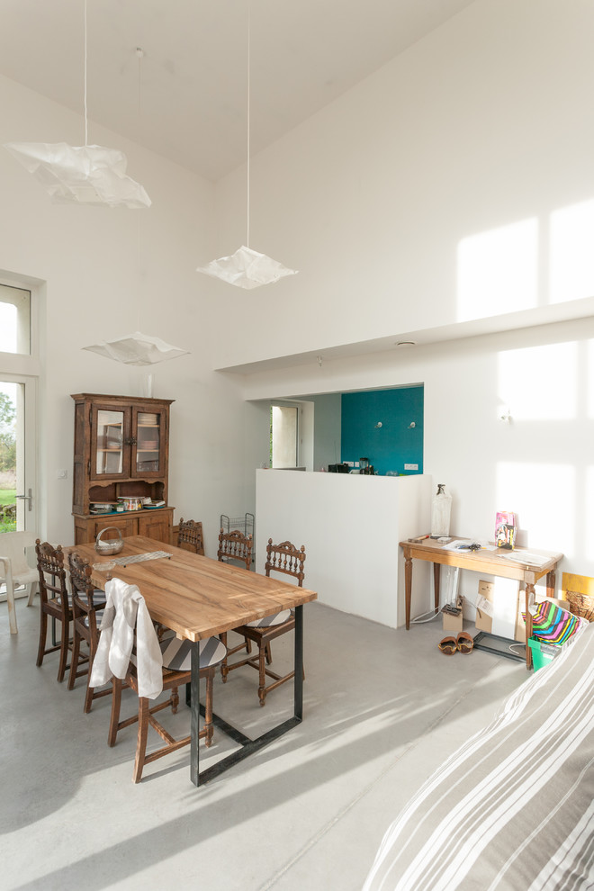 This is an example of a mid-sized contemporary open plan dining in Dijon with white walls and concrete floors.