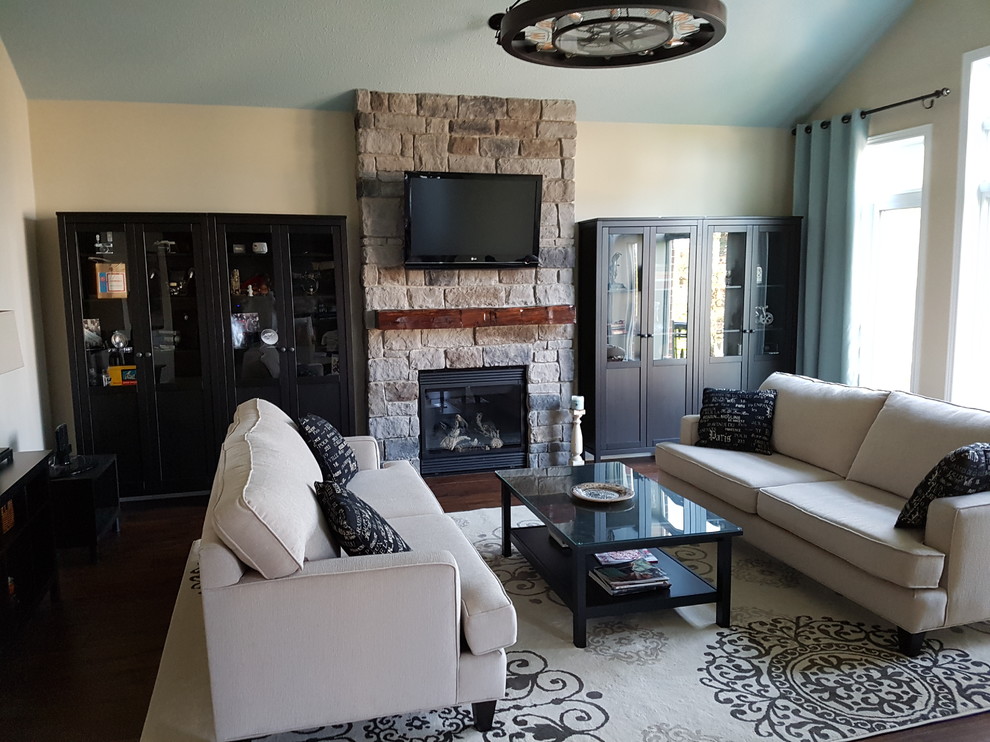 Inspiration for a mid-sized traditional open concept living room in Toronto with beige walls, medium hardwood floors, a standard fireplace, a stone fireplace surround, a wall-mounted tv and brown floor.