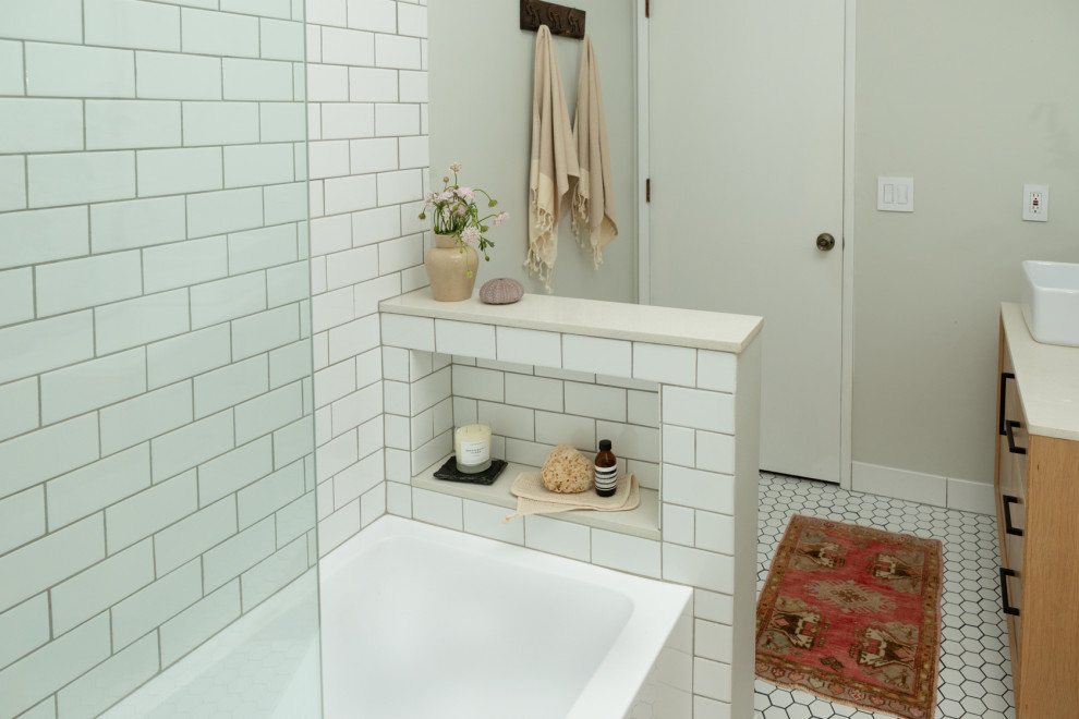 Идея дизайна: маленькая ванная комната в стиле ретро с плоскими фасадами, светлыми деревянными фасадами, ванной в нише, душем над ванной, унитазом-моноблоком, белой плиткой, керамической плиткой, серыми стенами, полом из керамогранита, настольной раковиной, столешницей из искусственного кварца, белым полом, душем с распашными дверями, белой столешницей, нишей, тумбой под одну раковину и напольной тумбой для на участке и в саду