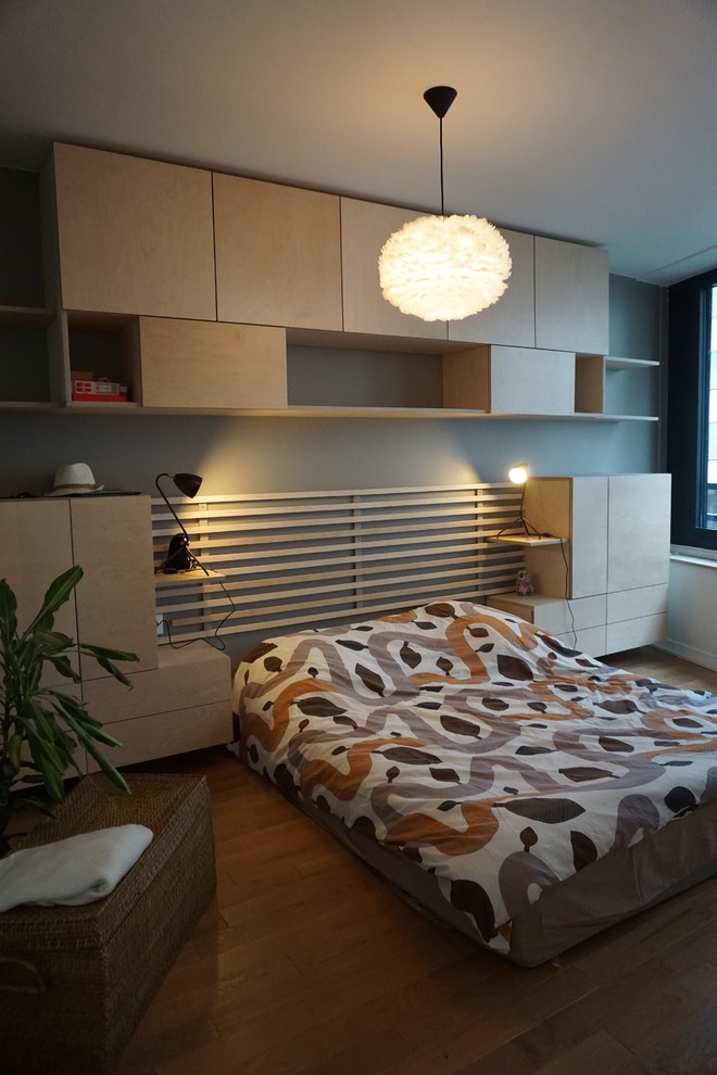 Mid-sized master bedroom in Paris with brown walls, medium hardwood floors and brown floor.
