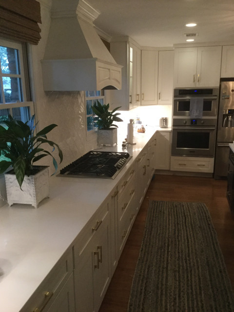 Large transitional l-shaped medium tone wood floor and brown floor eat-in kitchen photo in Atlanta with a farmhouse sink, shaker cabinets, white cabinets, marble countertops, white backsplash, stainless steel appliances, an island and white countertops