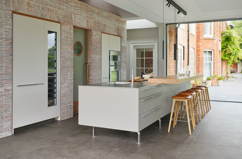 Inspiration for a large contemporary single-wall open plan kitchen in Wiltshire with an integrated sink, flat-panel cabinets, grey cabinets, stainless steel benchtops, stainless steel appliances and with island.