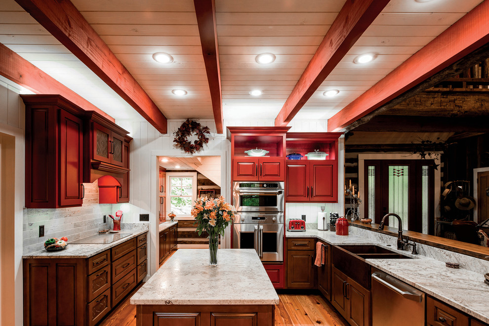 Example of a large mountain style l-shaped brown floor kitchen design with a farmhouse sink, raised-panel cabinets, brown cabinets, stainless steel appliances and an island