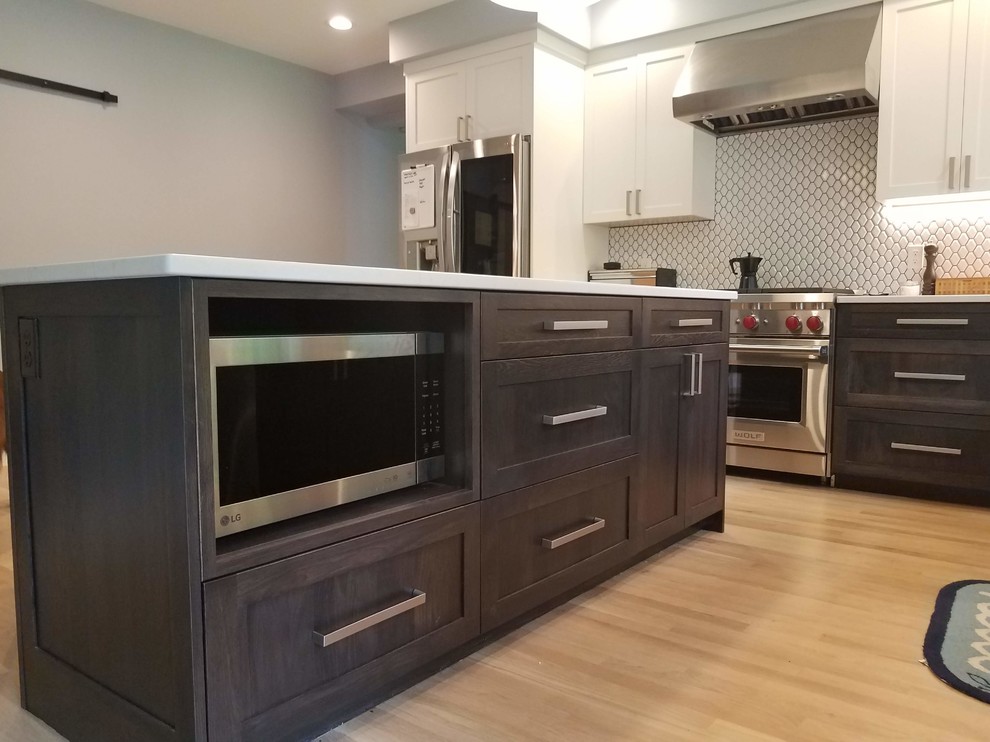 Design ideas for a large transitional l-shaped eat-in kitchen in Boston with an undermount sink, recessed-panel cabinets, brown cabinets, white splashback, porcelain splashback, stainless steel appliances, light hardwood floors, with island, beige floor, white benchtop and quartzite benchtops.