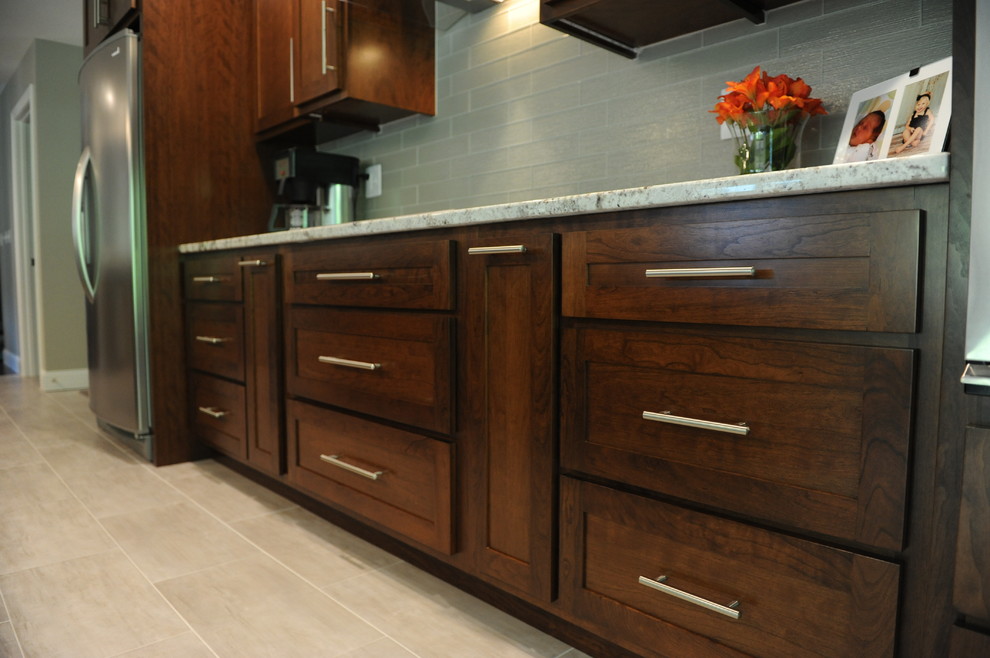 Huge transitional u-shaped ceramic tile home design photo in Chicago with an undermount sink, shaker cabinets, medium tone wood cabinets, granite countertops, gray backsplash, glass tile backsplash, stainless steel appliances and an island