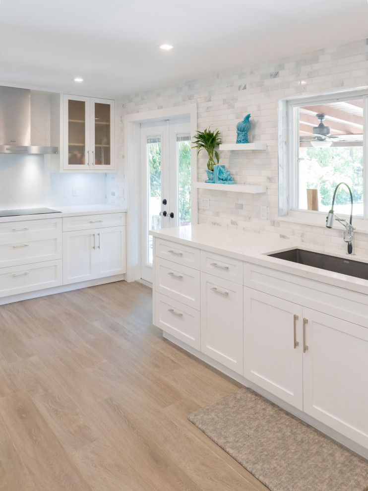 Example of a mid-sized transitional galley light wood floor kitchen pantry design in Miami with an undermount sink, shaker cabinets, white cabinets, quartz countertops, white backsplash, marble backsplash, stainless steel appliances and white countertops