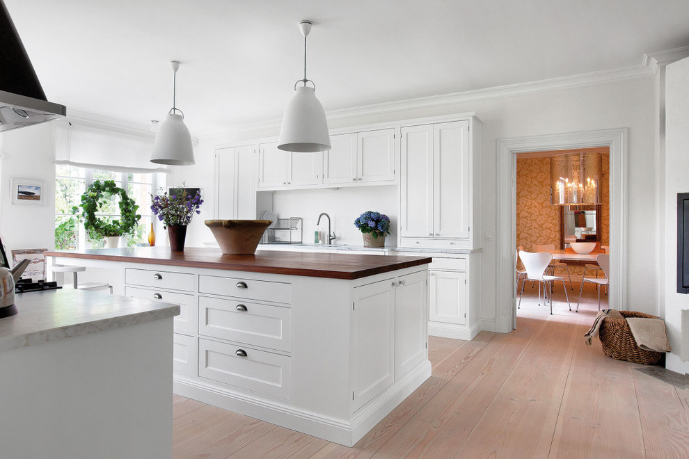Traditional kitchen in Malmo with recessed-panel cabinets, white cabinets and with island.