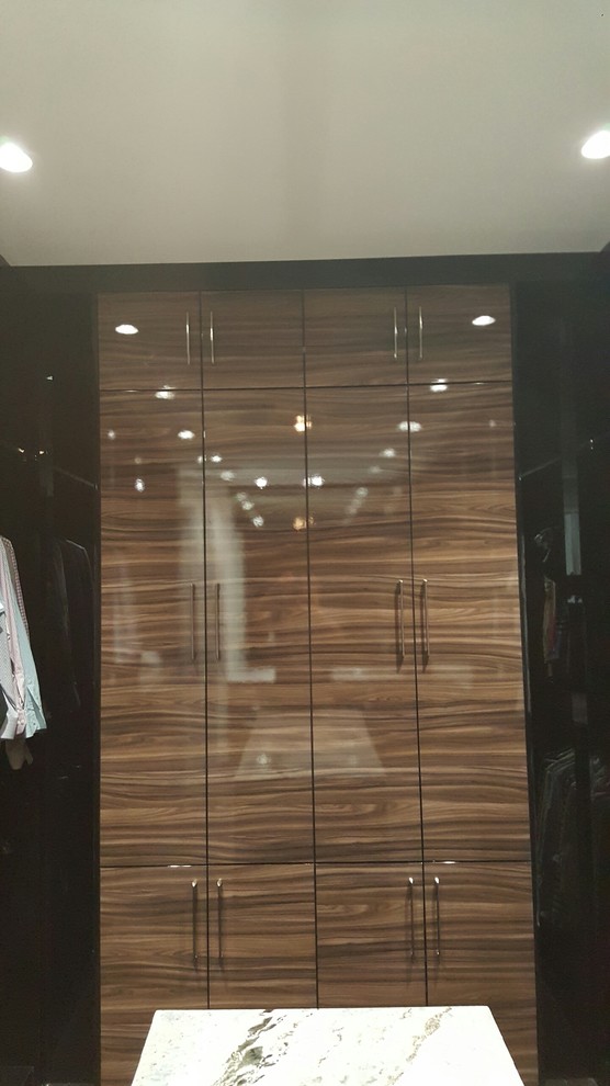 Photo of a mid-sized contemporary gender-neutral walk-in wardrobe in Miami with flat-panel cabinets, medium wood cabinets, medium hardwood floors and brown floor.