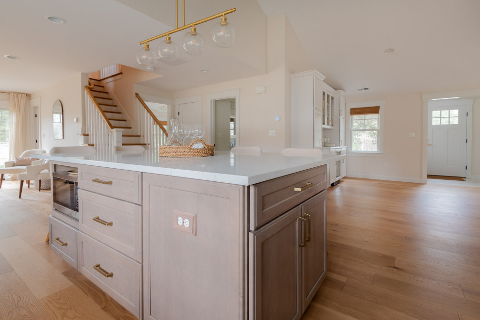 Inspiration for a huge transitional l-shaped light wood floor, brown floor and vaulted ceiling eat-in kitchen remodel in Boston with an undermount sink, shaker cabinets, white cabinets, quartz countertops, white backsplash, ceramic backsplash, paneled appliances, an island and white countertops
