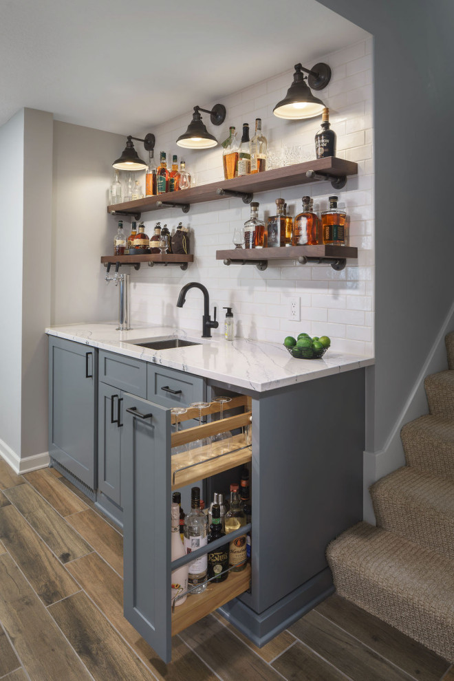Design ideas for a mid-sized country single-wall wet bar in Columbus with porcelain floors, brown floor, an undermount sink, shaker cabinets, grey cabinets, quartz benchtops, white splashback, ceramic splashback and white benchtop.