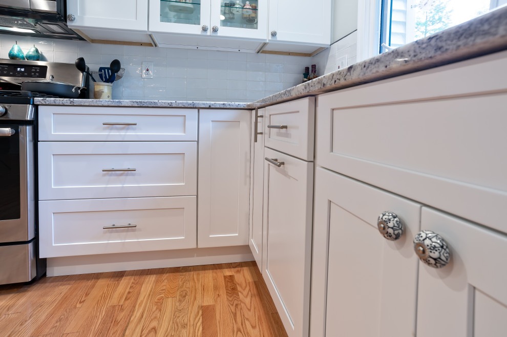 Inspiration for a mid-sized transitional u-shaped eat-in kitchen in Philadelphia with an undermount sink, shaker cabinets, white cabinets, quartz benchtops, white splashback, stainless steel appliances, medium hardwood floors, a peninsula, brown floor and multi-coloured benchtop.