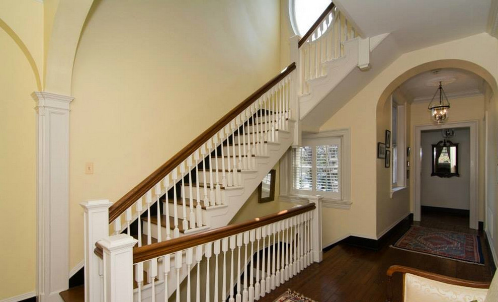 This is an example of a large traditional wood u-shaped staircase in Baltimore with painted wood risers and wood railing.