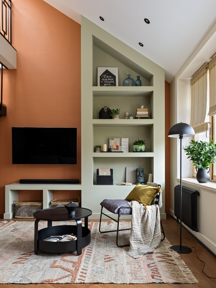 На фото: большая двухуровневая, объединенная гостиная комната в современном стиле с с книжными шкафами и полками, оранжевыми стенами, коричневым полом и обоями на стенах