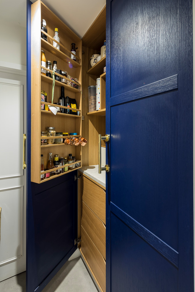 Design ideas for a large traditional single-wall kitchen pantry in London with a farmhouse sink, recessed-panel cabinets, blue cabinets, granite benchtops, mirror splashback, stainless steel appliances, ceramic floors, with island and grey floor.
