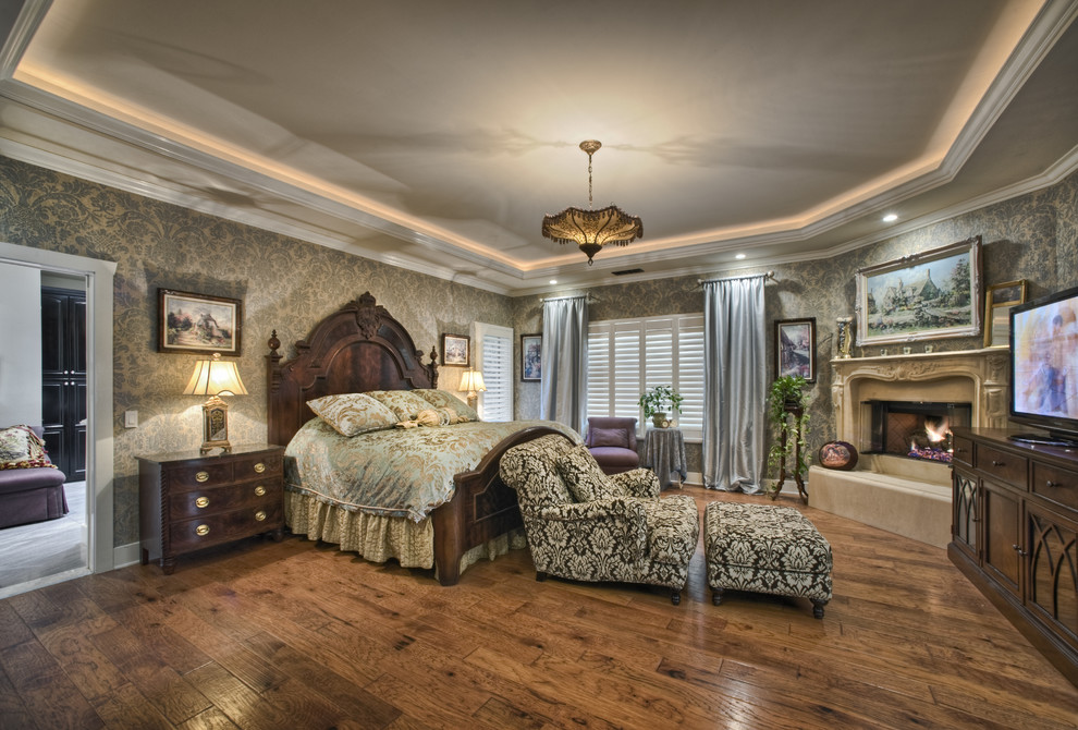 Inspiration for a large traditional master bedroom in Los Angeles with multi-coloured walls, medium hardwood floors, a standard fireplace, a stone fireplace surround and brown floor.