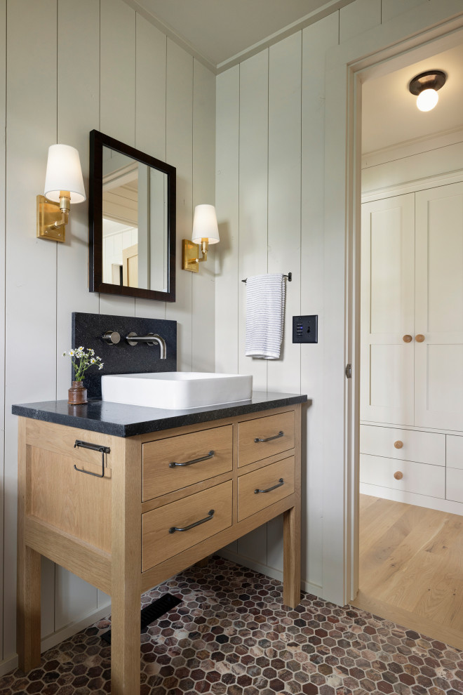 Example of a mountain style 3/4 black tile and ceramic tile marble floor, red floor, single-sink and shiplap wall alcove shower design in Minneapolis with flat-panel cabinets, light wood cabinets, a one-piece toilet, gray walls, a vessel sink, granite countertops, a hinged shower door, black countertops and a freestanding vanity