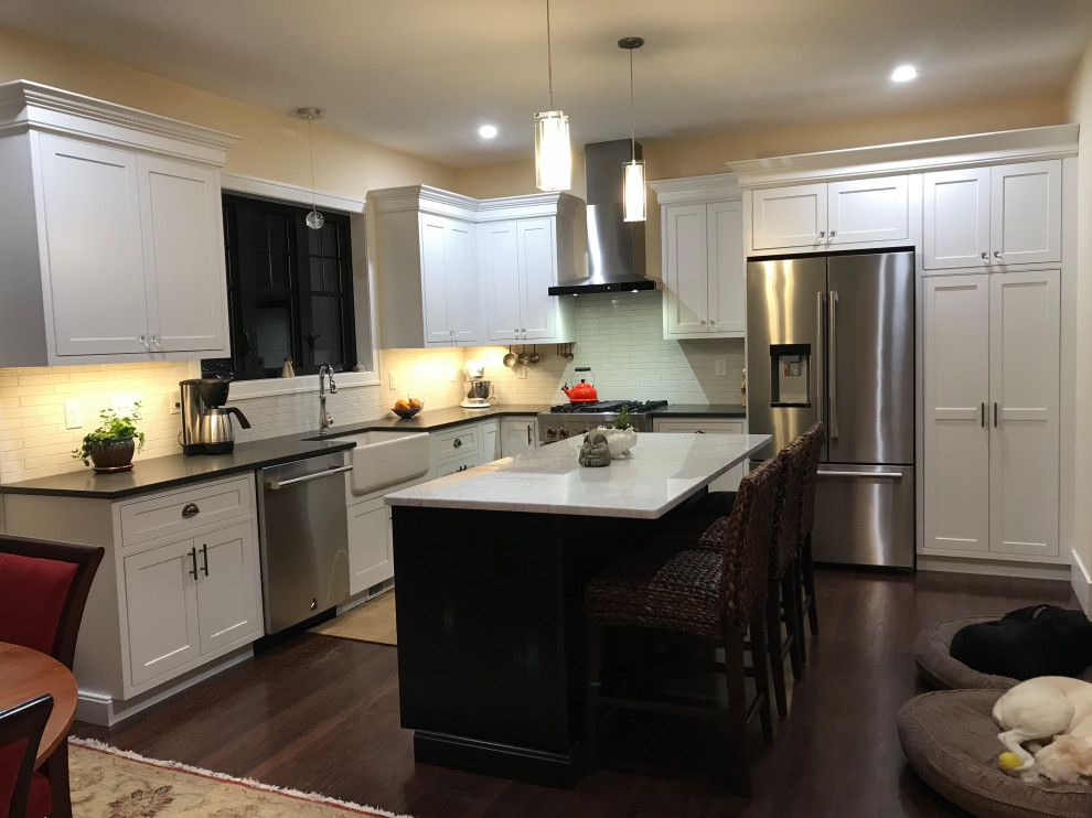 Eat-in kitchen - mid-sized transitional l-shaped laminate floor and brown floor eat-in kitchen idea with a farmhouse sink, beaded inset cabinets, white cabinets, quartz countertops, white backsplash, subway tile backsplash, stainless steel appliances and an island