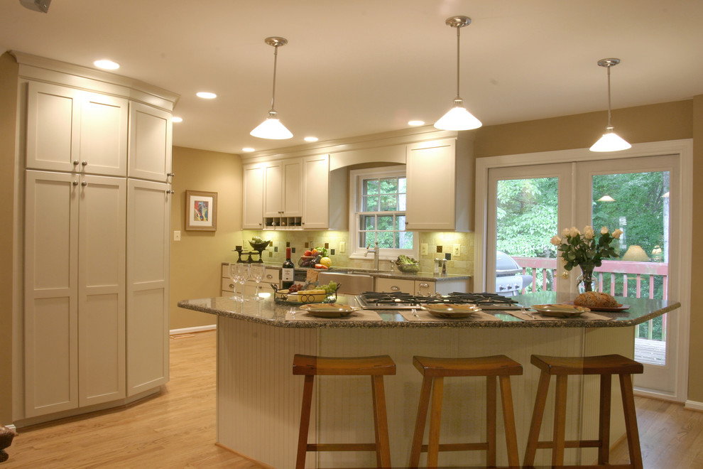 Eat-in kitchen - mid-sized traditional u-shaped light wood floor eat-in kitchen idea in DC Metro with a farmhouse sink, shaker cabinets, white cabinets, multicolored backsplash, stone tile backsplash, stainless steel appliances and an island